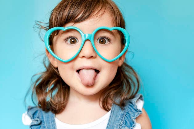 Weltkindertag am 20. September Portrait of cute little girl with tongue out and heart shaped glasses on blue background model released Symbolfoto  GEMF03178