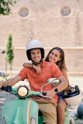 IMAGO Creative, Jahreszeit Sommer, Sommer in der Stadt Portrait of a smiling young couple on a vintage motor scooter model released Symbolfoto  JNDF00124