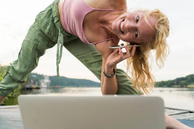 Young woman stretching and using laptop and cell phone on a jetty at a lake model released Symbolfoto  JOSF03614