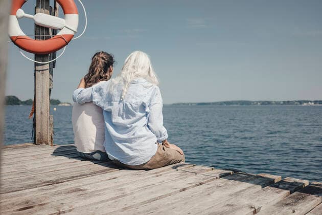 Mother and daughter looking at the sea, sitting on jetty, rear view model released Symbolfoto  JOSF03710