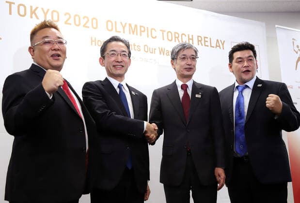 October 25, 2019, Tokyo, Japan - All Nippon Airways (ANA) president Yuji Hirako (2nd L) shakes hands with Japan Airlines (JAL) president Yuji Akasaka (2nd R) while Japanese comedy duo Sandwitchman members Mikio Date (L) and Takeshi Tomizawa (R) smile as they display the aircraft design to deliver Olympic flame from Greece in Tokyo on Friday, October 25, 2019. Judo Olympic gold medalist Tadahiro Nomura and women s wrestling Olympic goldmedalist saori Yoshida will carry Olympic flame back to Japan next March for Tokyo 2020 Olympics torch relay.  (115129910)