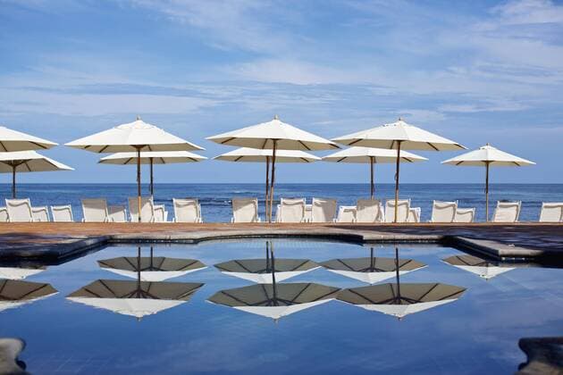 White beach umbrellas and lounge chairs at sunny ocean poolside, Punta de Mita, Nayarit, Mexico  Copyright: NikxWest fStopImages1849033