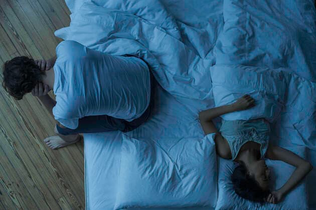 Man unable to sleep while wife sleeps comfortably unaware  Copyright: FrédéricxCirou B81982924
