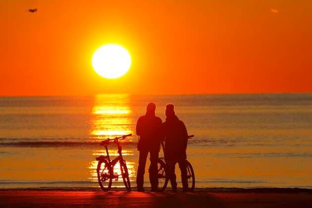 Pärchen mit Fahrrädern am Strand betrachtet den Sonnenuntergang, Nordsee, St. Peter-Ording, Nordseeküste, Nationalpark Schleswig-Holsteinisches Wattenmeer, Schleswig-Holstein, Deutschland, Europa Copyright: imageBROKER/JustusxdexCuveland ibxuve05068096.jpg