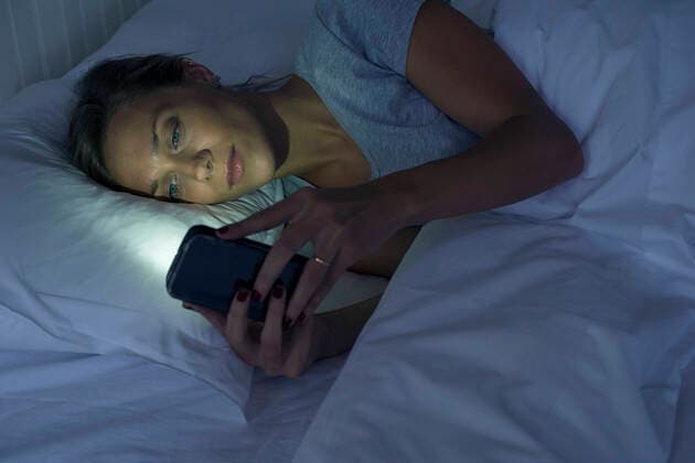 Woman lying in bed using smartphone  Copyright: FrédéricxCirou B97888723
