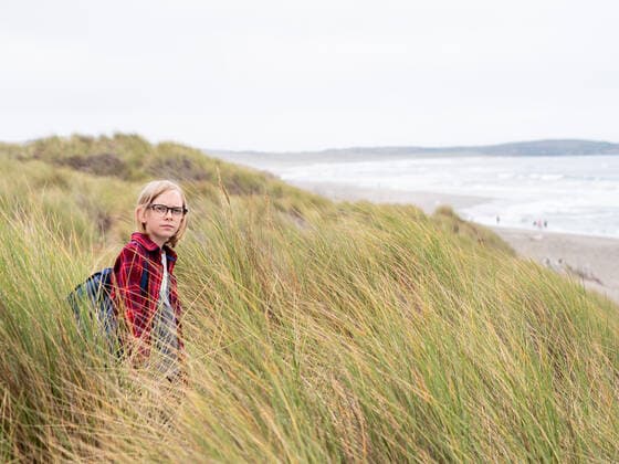 Tween Boy looking at camera standing in tall sea grass on the coast United States, California CR_CHEREN191021-176249-01