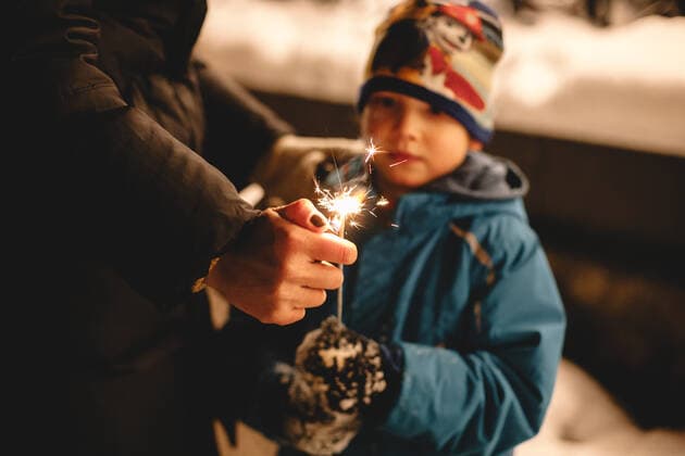 Mother igniting sparkler held by her son outdoors in winter Kyiv, Ukraine CR_DMBE191028-208601-01