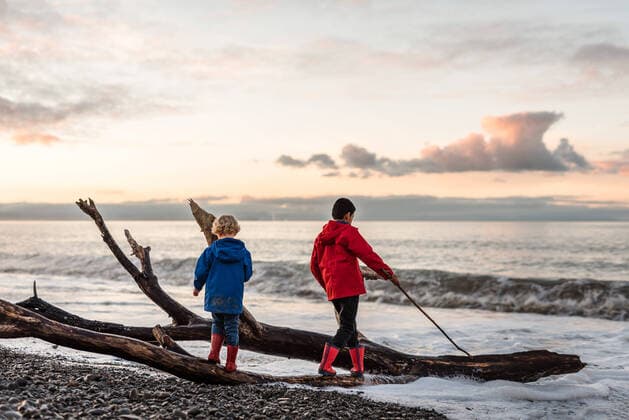 Brothers playing on rocky beach at dusk New Zealand, Hawke s Bay CR_JUCR191017B-214759-01