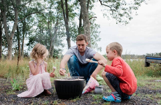 dad cooking marshmallows with his kids over a campfire bbq outdoors Sweden, Stockholm County, Norrtälje CR_RABE191011-182194-01