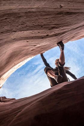 A woman canyoneer starts an exposed downclimb on slick sandstone walls United States, Utah CR_SUST191016-170005-01