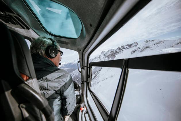 IMAGO Creative: Alternativer Wintersport Helicopter pilot looks out side window while flying over alpine lake. Canada, ???????? R_JDIP191011B-209798-01