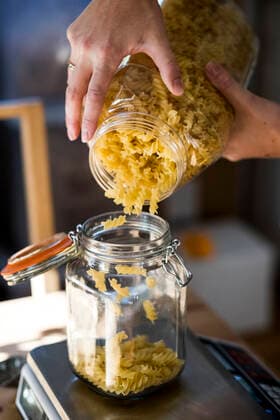 Close up of person pouring Fusilli pasta into glass jar on kitchen scales. Close up of person pouring Fusilli pasta into glass jar on kitchen scales.  59282