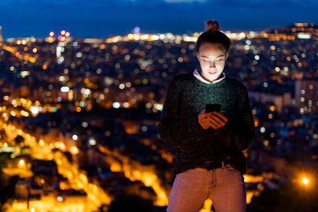 Young woman using cell phone at night above the city, Barcelona, Spain model released Symbolfoto  GIOF07689
