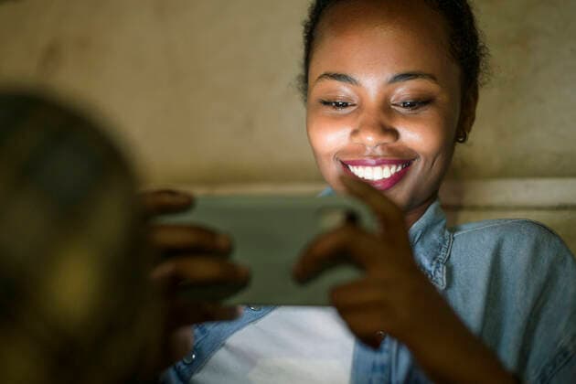 Creative Highlights Symbolfotos Portrait of happy young woman using smartphone by night, Lisbon, Portugal model released Symbolfoto  UUF19139