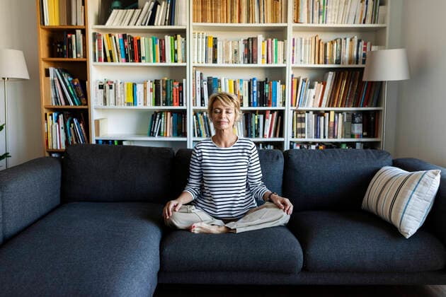 Mature woman practicing yoga on couch at home model released Symbolfoto property released  VABF02405