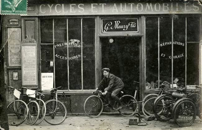 CYCLISME annees 1900 Magasin de cycles et automobiles. Photographie anonyme pour une carte postale vers 1907. Credit : Collection IM KHARBINE-TAPABOR. *** CYCLING 1900s Cycle and car shop Anonymous photograph for a postcard around 1907 Credit Collection IM KHARBINE TAPABOR  KH177091