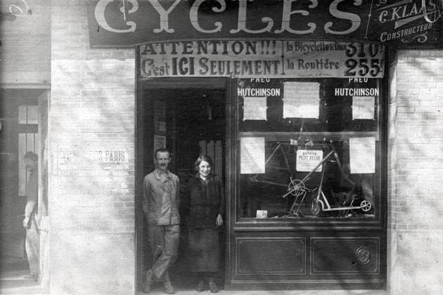 MAgasin de cycles annees 20 Couple devant leur magasin de cycles, sur la vitrine : C. Klaas constructeur, Attention c est ici seulement la bicyclette pour 310 f, la Routiere 255 f . Boulevard Victor a Paris. carte photographique vers 1920. Credit KHARBINE TAPABOR *** MAgasin of bicycles in the 20s Couple in front of their bicycle shop, on the window C Klaas manufacturer, Attention it is here only the bicycle for 310 f, the Road 255 f Boulevard Victor in Paris photographic map around 1920 Credit KHARBINE TAPABOR  KH253064