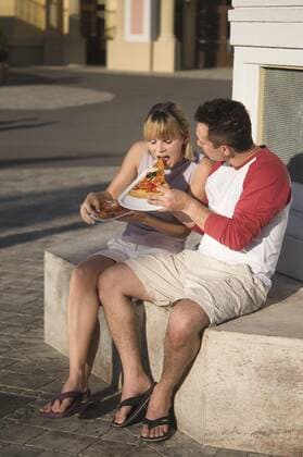 Junges Paar isst eine Pizzaschnitte - Young couple eating pizza outdoors