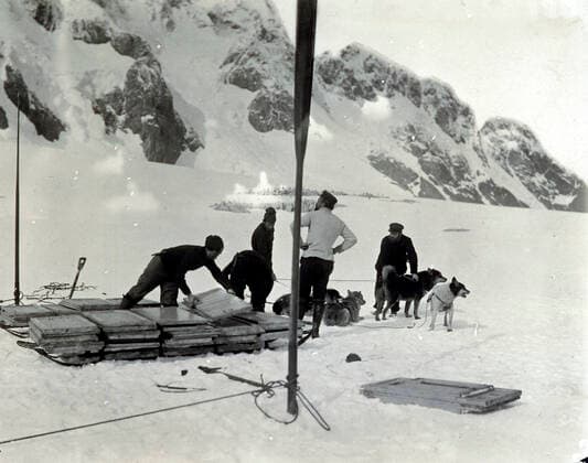 Commandant CHARCOT Les membres de l expedition Charcot au pole sud de 1903 a 1905 transportent par traineaux des pans de la maison a construire pour avoir un pied-a-terre. Photographie PLENEAU P. (19-20 s.). Credit: KHARBINE-TAPABOR COLL. S. Kakou.