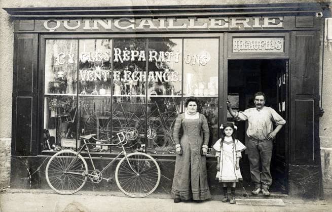 QUINCAILLERIE annees 10 Couple avec un enfant devant une boutique de Quincaillerie, specialisee dans les cycles. Photographe anonyme pour une carte postale vers 1912. Credit : Collection IM KHARBINE-TAPABOR *** QUINCAILLERIE années 10 Couple with a child in front of a hardware store, specialized in cycles Anonymous photographer for a postcard around 1912 Credit Collection IM KHARBINE TAPABOR  KH176993