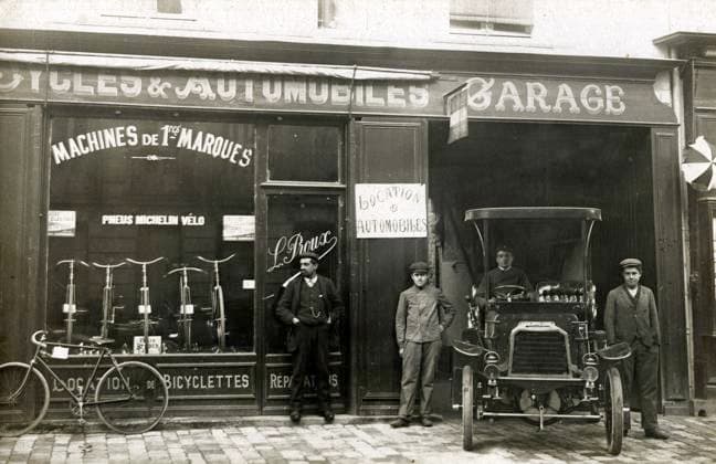 GARAGE annees 1900 Depart d un garage et magasin de cycles. Photographie anonyme pour une carte postale vers 1907. Credit : Collection IM KHARBINE-TAPABOR. *** GARAGE 1900s Departure from a garage and bicycle shop Anonymous photograph for a postcard around 1907 Credit Collection IM KHARBINE TAPABOR  KH177079