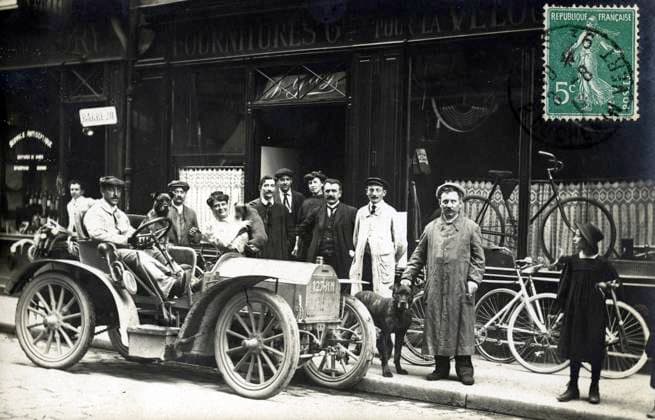 TRANSPORT annees 10 Homme en automobile devant un magasin de cycles. Photographie anonyme pour une carte postale vers 1910. Credit : Collection IM KHARBINE-TAPABOR. *** TRANSPORT in the 10s Man by car in front of a bicycle shop Anonymous photograph for a postcard around 1910 Credit Collection IM KHARBINE TAPABOR  KH177086