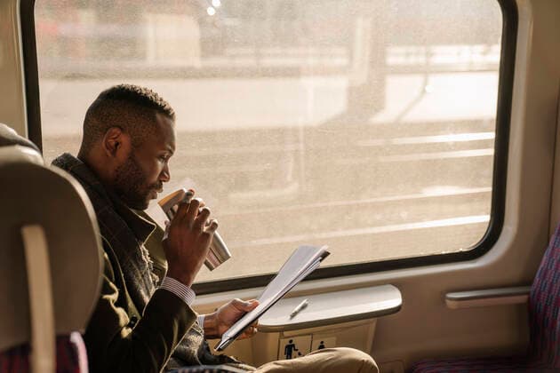 IMAGO Creative: Corporate: Klimaschutz, Digitalisierung und Urbanisierung Stylish businessman with reusable cup and documents in a train model released Symbolfoto  AHSF01639