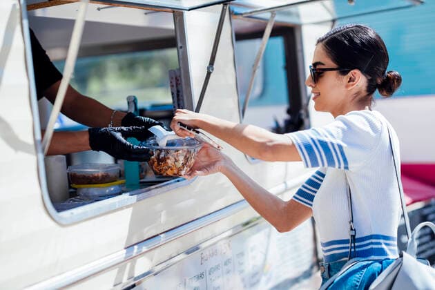 Creative Highlights Symbolfotos Young woman buying take away food from a street food stand model released Symbolfoto  JSMF01391