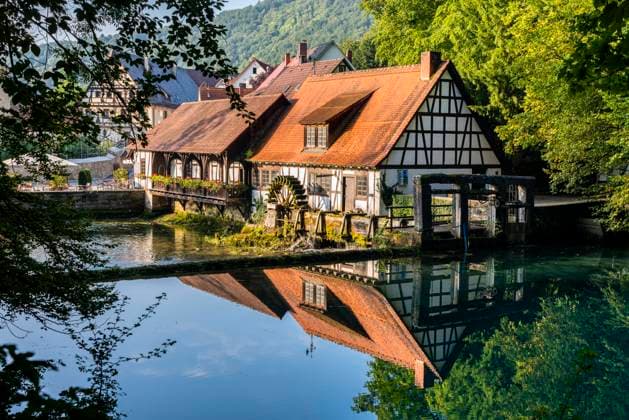 Germany, Baden-Wurttemberg, Blaubeuren, Countryside cottages reflecting in shiny river  STSF02281