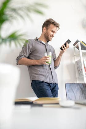 Smiling man using smartphone in office model released Symbolfoto property released  VPIF01788