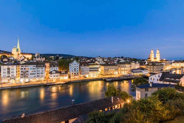 Switzerland, Canton of Zurich, Zurich, River Limmat and old town buildings along illuminated Limmatquai street at dusk  WDF05553