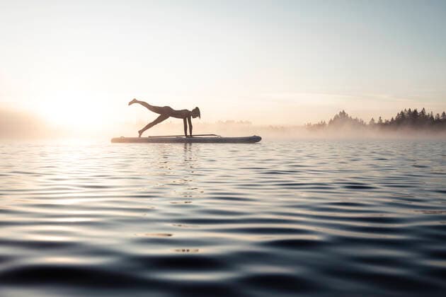 Woman practicing paddle board yoga on lake Kirchsee in the morning, Bad Toelz, Bavaria, Germany model released Symbolfoto  WFF00201