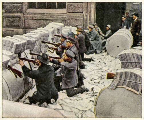 ALLEMAGNE 1919 Janvier 1919 : barricade lors de combats de rue a Berlin (revolution spartakiste). au cours d un affrontement de rue les combattants se protegent derriere une barricade faire de rouleaux de papier et de piles de journaux. La scene se passe devant l immeuble du VORWATS, l organe officiel du SPD, bloque par les insurges pour avoir publie des articles hostiles aux spartakistes. Photographie tiree de l album d images allemand Die Nachkriegszeit 1918-1934 . Credit : Collection KHARBINE-TAPABOR.