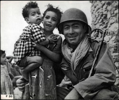 GUERRE D ALGERIE Soldat francais avec enfants algeriens. Photographie anonyme vers 1958 pour la propagande francaise. Credit : Collection IM Kharbine-Tapabor. *** ALGERIAN WAR French soldier with Algerian children Anonymous photograph around 1958 for French propaganda Credit Collection IM Kharbine Tapabor  KH202444