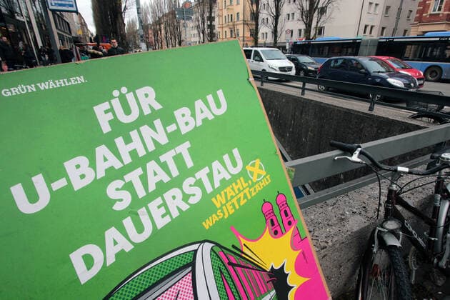 Kommunalwahl in Bayern am 15.03.2020: Wahlplakat der Partei Bündnis 90 die Grünen mit Aufschrift für U-Bahn Bau statt Dauerstau an der Haltestelle Giselastraße auf der Leopoldstraße mit Stau in München Schwabing, Bayern, Deutschland