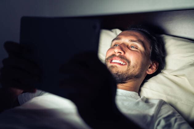 Young handsome and tired man with a beard smiling at a tablet at night Wlodawa, Lubelskie, Poland CR_QLKC191113B-234649-01