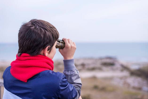 Playful boy looking through binoculars to the sea Barcelona, Spain CR_RAFE191114-235815-01