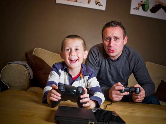 Father and son playing Video Games Father and son playing Video Games sitting in the Sofa  Copyright: xgemenacomx 1348810