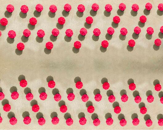 Aerial view of arrangement of red beach umbrellas on sandy beach  KNTF04088