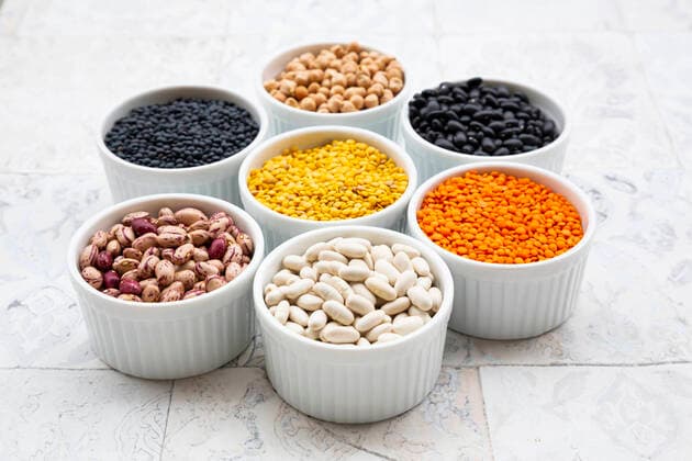 Various legumes in bowls: chickpeas, cannellini beans, quail beans, black beans, yellow lentils, red lentils, black lentils  LVF08482