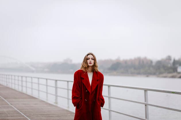IMAGO Creative: Clickbait, Modetrends Portrait of young woman wearing red coat on a bridge during rainy day model released Symbolfoto  TCEF00026