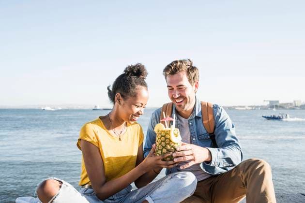 Happy young couple sitting at the waterfront sharing a drink in a pineapple, Lisbon, Portugal model released Symbolfoto  UUF19849