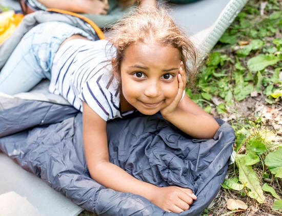 Little girl lying on sleeping bag, looking at camera model released Symbolfoto  WESTF24487
