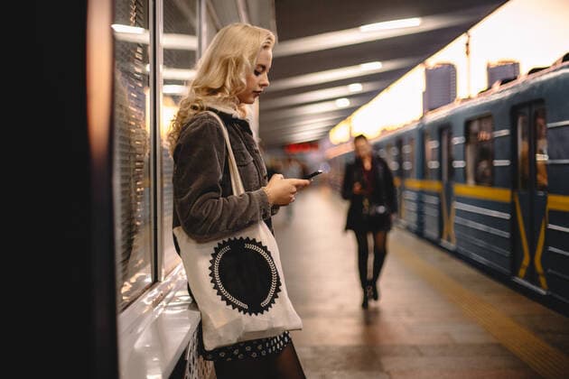 Young woman using smart phone while standing at subway station CR_DMBE191216A-249812-01