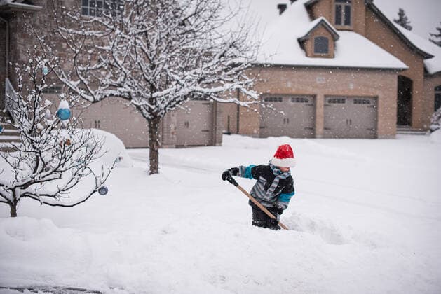 Boy in Santa hat shovelling snow in front yard on a winter day. Kingston, ON, Canada CR_DOHO200110A-281158-01