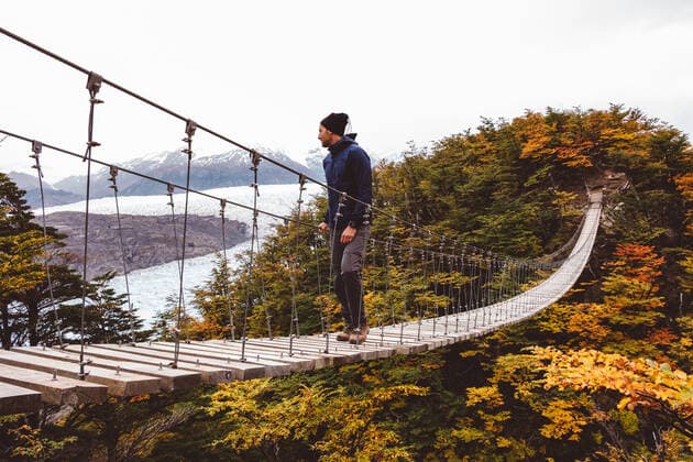 Man standing on suspension bridge in mountains Torres del Paine, Magallanes y Antartica Chilena, Chile CR_FAKODA191216-246032-01