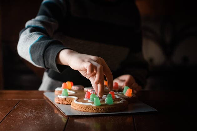 IMAGO Creative: Kimawandel - Weihnachten, Weihnachtsessen vegan small hands touching a gumdrop on a gingerbread man cookie on table Marshalltown, IA, United States CR_KAVO191211-258390-01