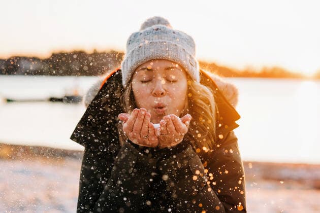 Woman blowing golden snow at sunset in winter Stockholm, Stockholm County, Sweden CR_RABE191212-252802-01