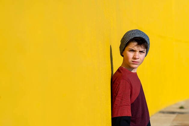 Teen with wool cap leaning against a yellow wall while looking camera Barcelona, CT, Spain CR_RAFE200103D-132317-01