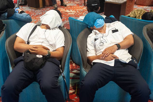 31.01.2020, Singapur, Republik Singapur, Asien - Zwei Flugreisende haben ihre Gesichter mit Tuechern abgedeckt und schlafen im Ankunftsbereich des Terminal 1 am Flughafen Changi in Sesseln. Einer von ihnen traegt zusaetzlich eine Atemschutzmaske, um sich vor einer Ansteckung mit dem Coronavirus zu schuetzen.